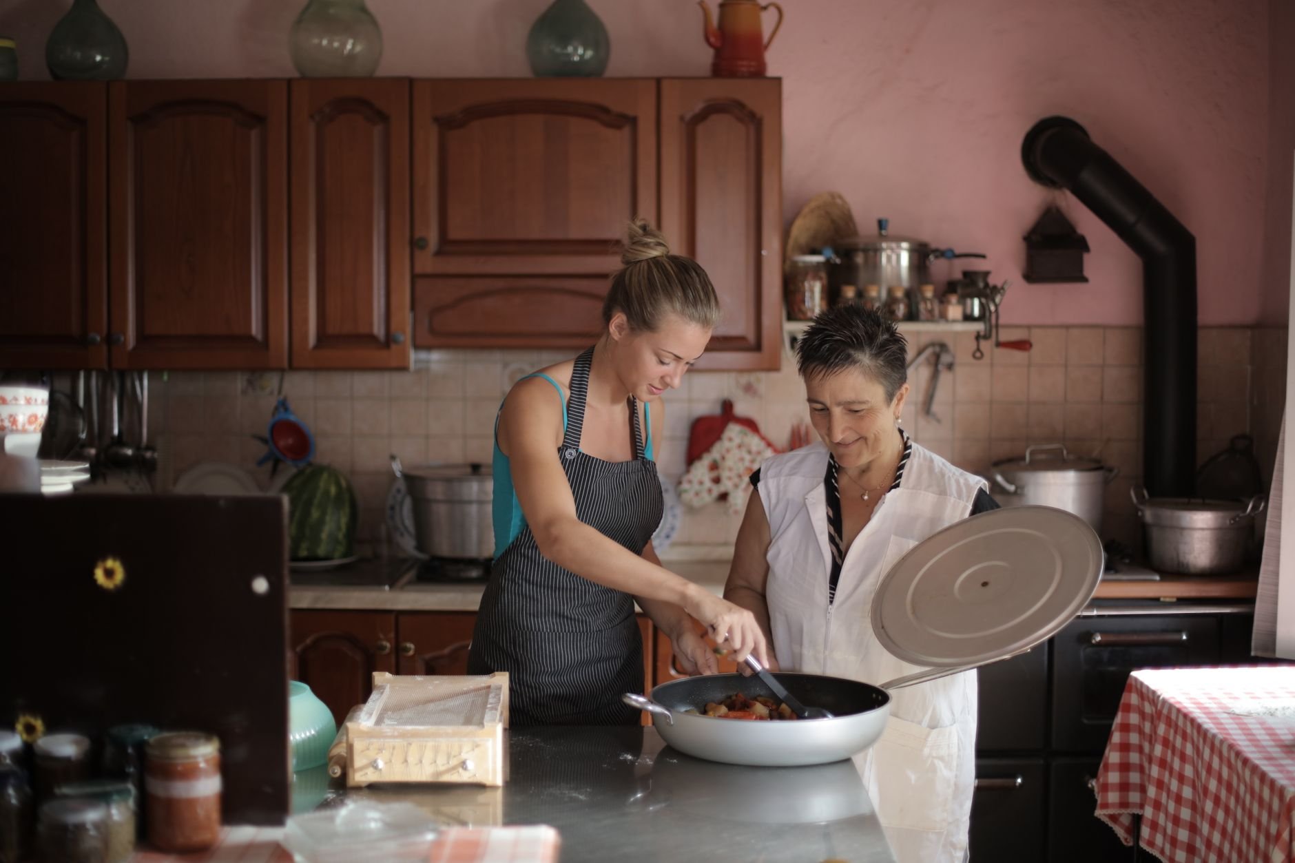 Mother and daughter enjoy cooking together in a cozy, rustic kitchen setting.
